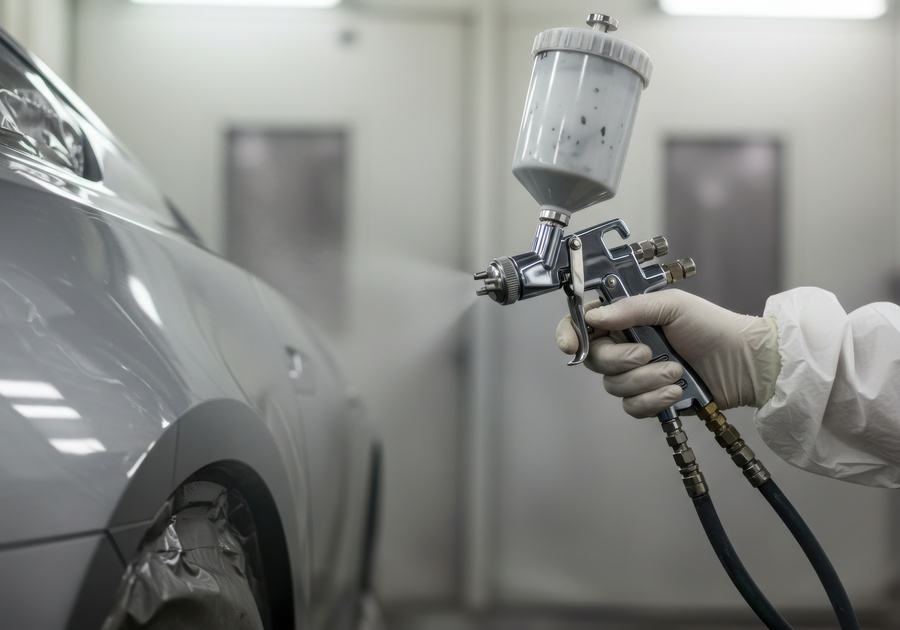 Professional restoration expert applying paint to a car panel