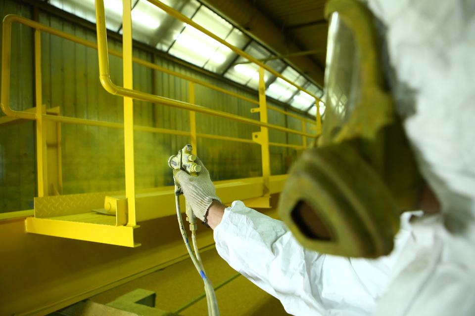 The painter applying electrostatic coat on industrial equipment