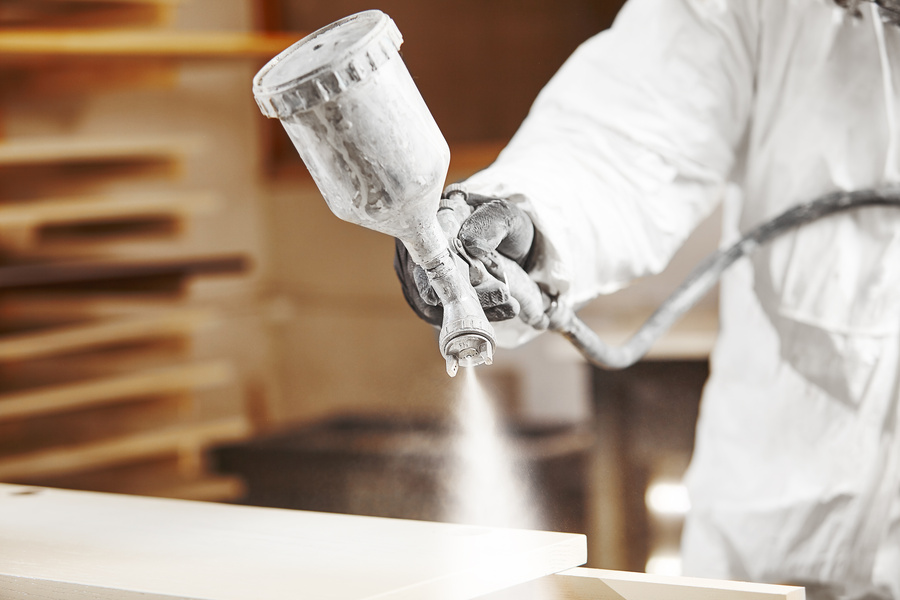 Man working with electrostatic paint spray gun, spraying on door and window frame