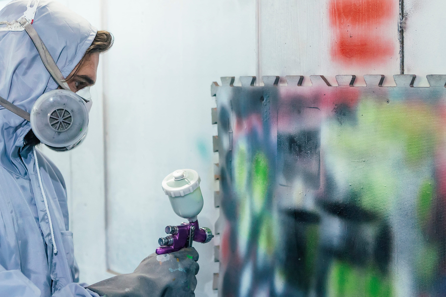 Electrostatic painting expert at work painting metal with paint gun