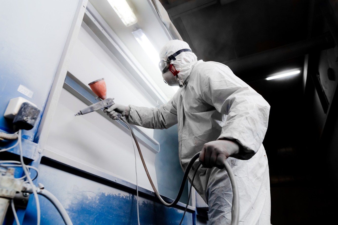 electrostatic painting expert paints metal impact door with a spray gun
