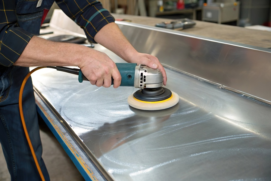 Worker polish metal surface with tool.